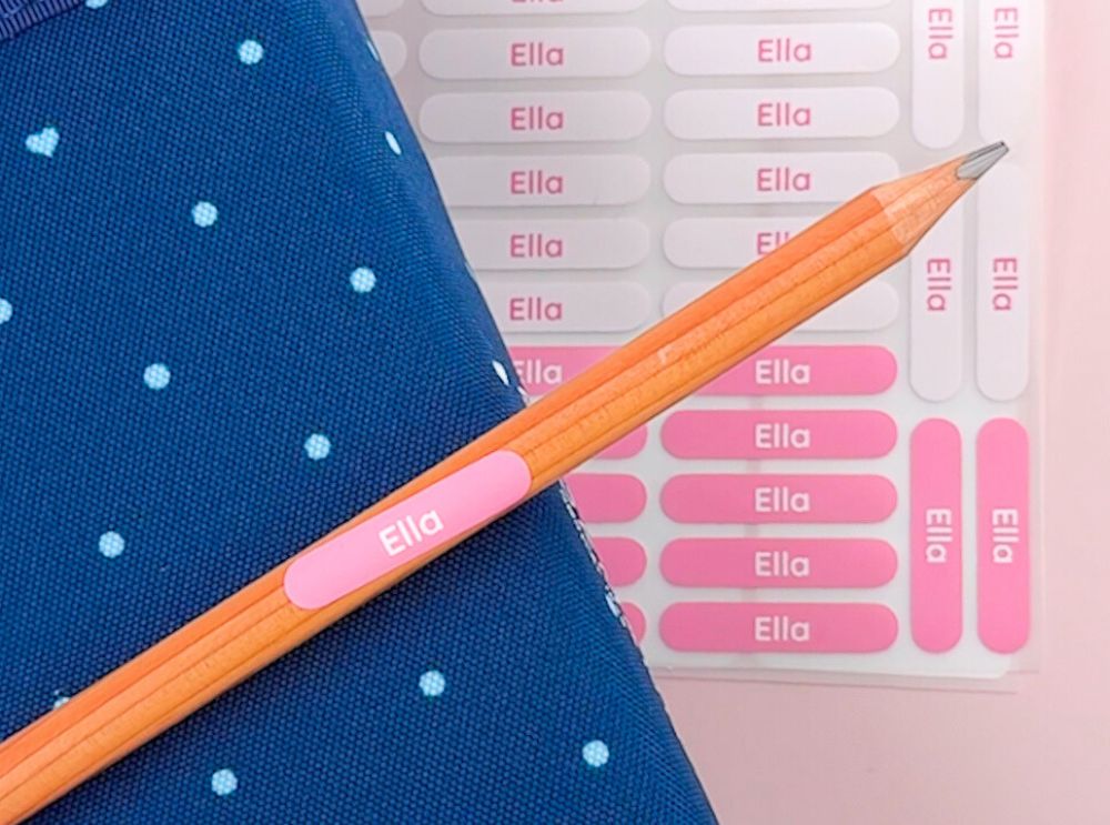 Pink pencil name label with the name Ella, placed on a pencil next to a matching sticker sheet