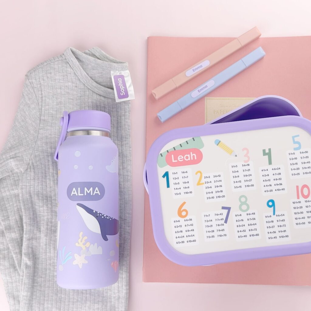 Two types of name labels along with a personalized water bottle and lunch box featuring names printed directly on the items